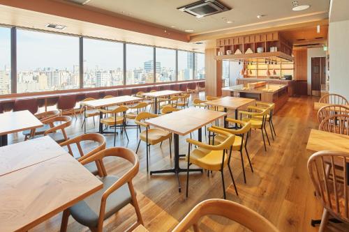 a restaurant with tables and chairs and windows at hotel MONday Premium Ueno Okachimachi in Tokyo
