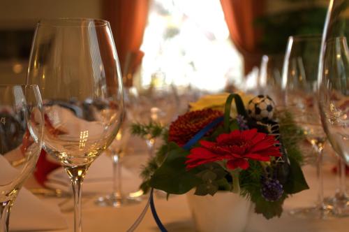 a table with wine glasses and a vase with red flowers at Hotel Restaurant Bären in Freudenstadt