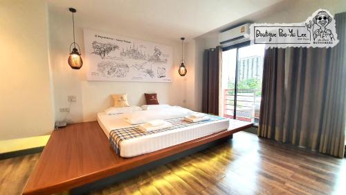 een slaapkamer met een bed en een groot raam bij Boutique Poo-Yai Lee in Bangkok
