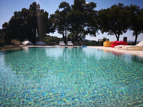 una gran piscina de agua con sillas y árboles en Villa Maria, en Dorgali