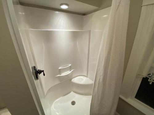 a white bathroom with a toilet and a shower at Twin Lakes Creamery, Grill & Inn in Leitchfield