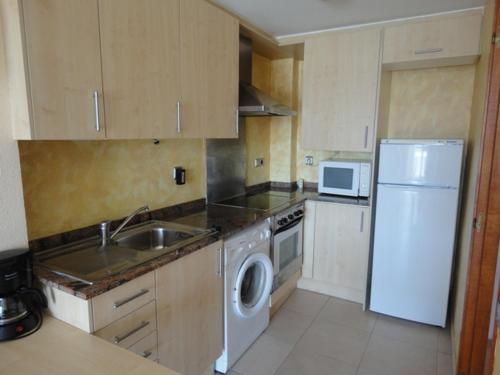 a kitchen with a white refrigerator and a sink at Costa Dorada Miami in Miami Platja