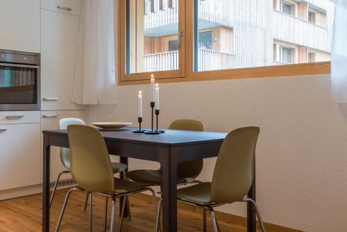 a dining room table with four chairs and two candles at Montela Apartment-Hotel & Resort in the holiday region Saas-Fee Saastal in Saas-Grund