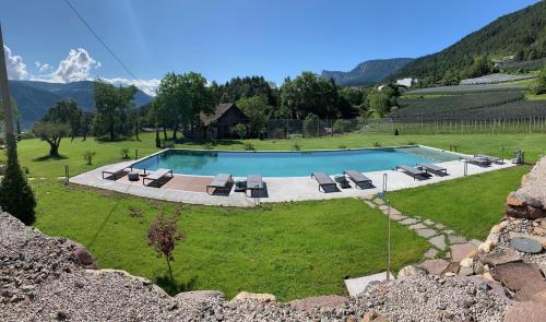 - une piscine dans un champ avec des chaises et une maison dans l'établissement Residence Liesy, à Tesimo