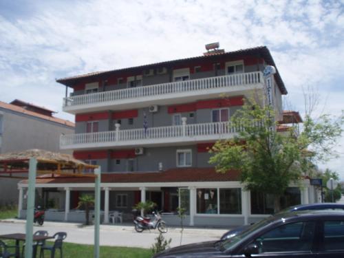 ein großes rotes Gebäude mit einem weißen Balkon in der Unterkunft Hotel Ifigenia Paralia Katerinis plaz in Paralia Katerinis