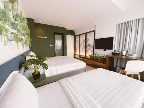 um quarto de hotel com duas camas e uma televisão de ecrã plano em The Atelier Boutique Hotel em Kota Kinabalu