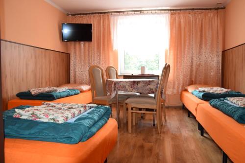 Pokój z łóżkami, stołem i oknem w obiekcie Ośrodek Wypoczynkowy Pod Szczelińcem w mieście Karłów