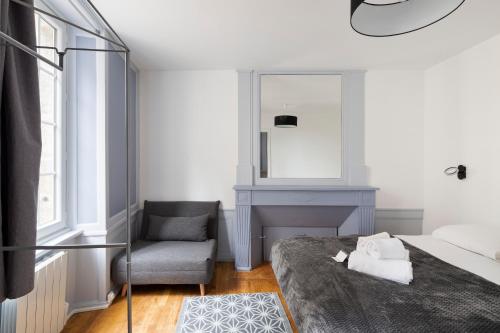 une chambre avec un lit, une chaise et un miroir dans l'établissement Le Dinanais - Cocon dans l'Intra Muros, à Saint-Malo