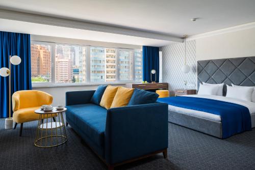 オデッサにあるOK オデッサの青いソファとベッドが備わるホテルルームです。