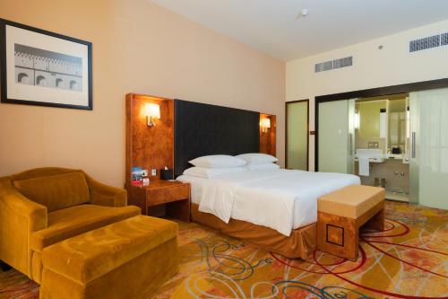 a hotel room with a bed and a chair at Millennium Airport Hotel Dubai in Dubai