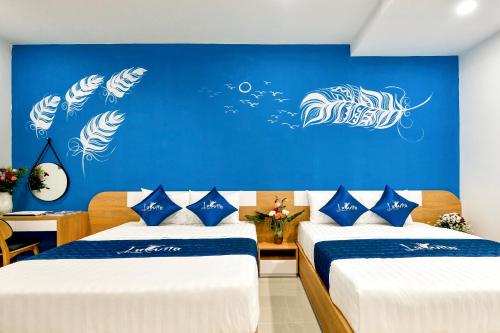 a bedroom with two beds and a blue wall at La Vita Hotel in Vung Tau