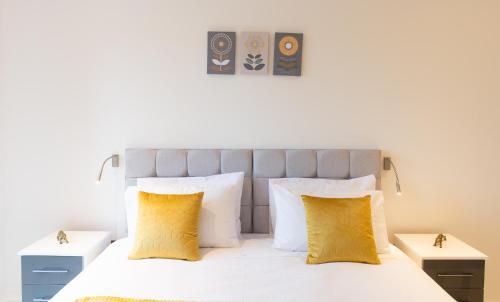 1 dormitorio con cama blanca y almohadas amarillas en Beautiful 1 Bed Apartment in Centre of St Albans - Free Parking - 5 min walk to St Albans city centre & Railway station, 15mins drive to Harry Potter World - Free Super-fast Wifi, en Saint Albans