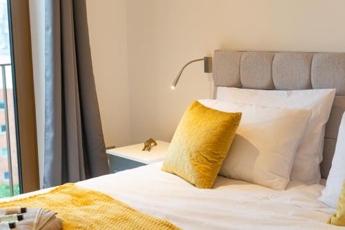 Dormitorio con cama con almohada amarilla en Beautiful 1 Bed Apartment in Centre of St Albans - Free Parking - 5 min walk to St Albans city centre & Railway station, 15mins drive to Harry Potter World - Free Super-fast Wifi, en Saint Albans