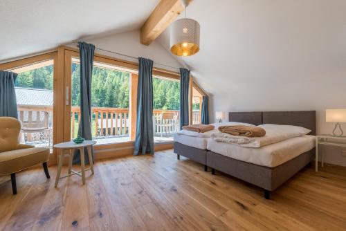 a bedroom with a bed and a large window at Montela Hotel & Resort - Apartments in Saas-Grund