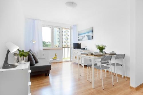 ein weißes Wohnzimmer mit einem Tisch und Stühlen in der Unterkunft Elite Apartments Gospody in Danzig