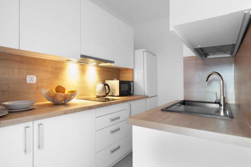 a kitchen with white cabinets and a counter top at Elite Apartments Gospody in Gdańsk