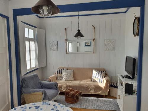 a living room with a couch and a tv at Palheiro Costa Nova in Costa Nova
