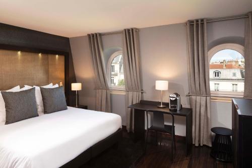 a hotel room with a bed and two windows at Hôtel Elysées Régencia in Paris