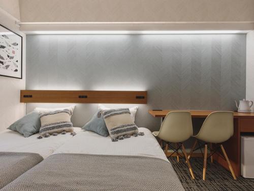 two beds in a bedroom with a desk and chairs at 3rd PLACE by HIDEOUT in Fujisawa
