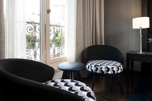 a living room with two chairs and a window at Hôtel Elysées Régencia in Paris