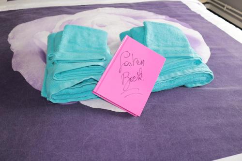 a pile of towels on a bed with a sign at B&B Den Boskant in Zandbergen