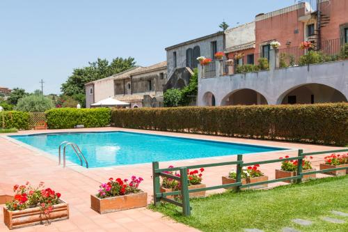 a swimming pool with flowers in a yard at Etna Hotel in Giarre