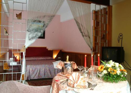 una habitación con una mesa con flores y una cama en Hotel Costellazioni, en Troina