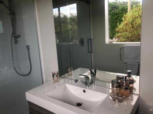 a white bathroom with a sink and a mirror at Southland Organic Farmstay in Invercargill