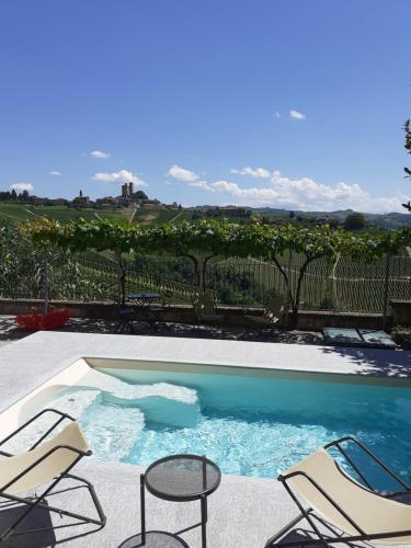 a swimming pool with two chairs and a table at Agriturismo I Grappoli in Serralunga d'Alba