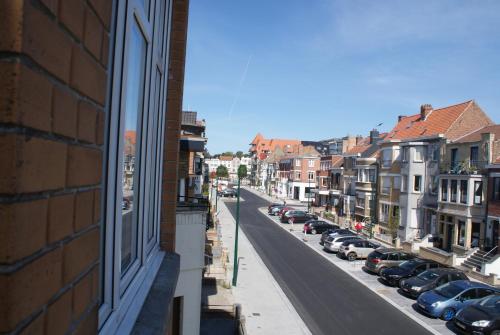 Una calle de la ciudad con coches aparcados al costado de un edificio. en Studio Le Lavandou, en De Panne