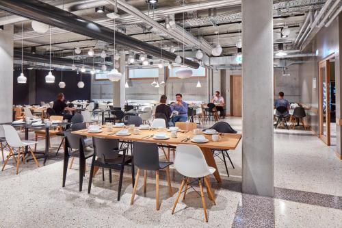 a group of people sitting at tables in a restaurant at aletto Hotel Potsdamer Platz in Berlin