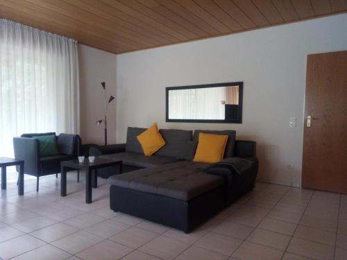 a living room with a black couch and yellow pillows at Apartment am Vechtesee in Schüttorf