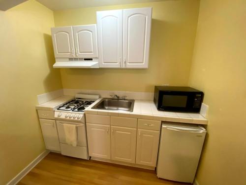 a kitchen with white cabinets and a sink and a microwave at Hollywood Celebrity Hotel in Los Angeles