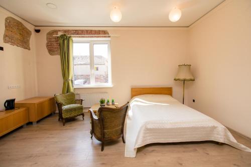 um quarto com uma cama, uma cadeira e uma janela em Old Town Apartments em Alytus
