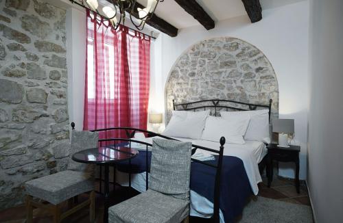 1 dormitorio con cama, mesa y pared de piedra en Heritage Residence in Center with pool, en Vodice
