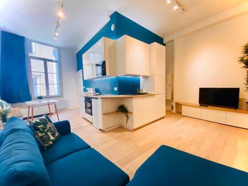 a living room with a blue couch and a tv at Suite Bayle - Standing - Hyper centre in Montpellier