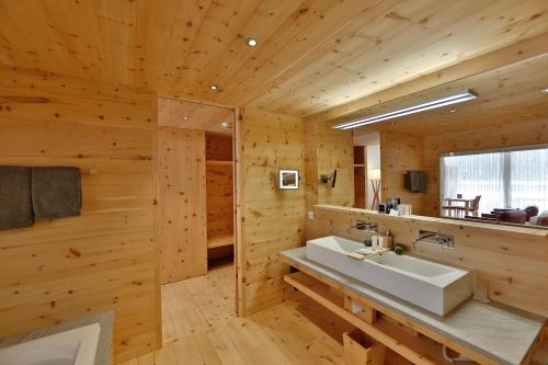 un bagno con lavandino bianco in una camera in legno di Relais & Châteaux IN LAIN Hotel Cadonau a Brail