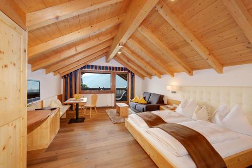 a bedroom with a large bed and a living room at Small Hotel Sonne in Tirolo