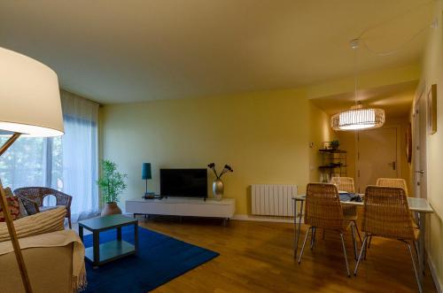 uma sala de estar com um sofá e uma mesa com cadeiras em Devesa Park Apartment with Private Parking em Girona