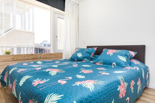 a bedroom with a blue comforter with pink flamingos on it at Aan Zee in Bergen aan Zee