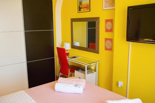 a yellow room with a desk and a mirror at Apartments Vinka in Sveti Filip i Jakov