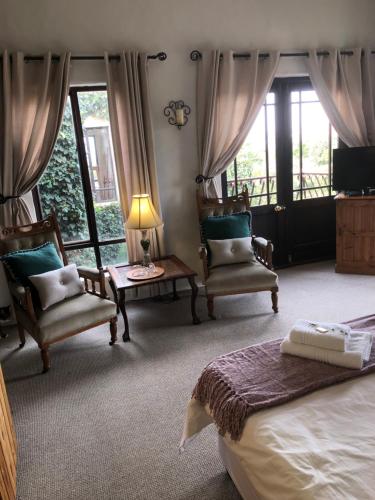 - une chambre avec un lit, deux chaises et une télévision dans l'établissement Dio Dell Amore Guest House, à Jeffreys Bay