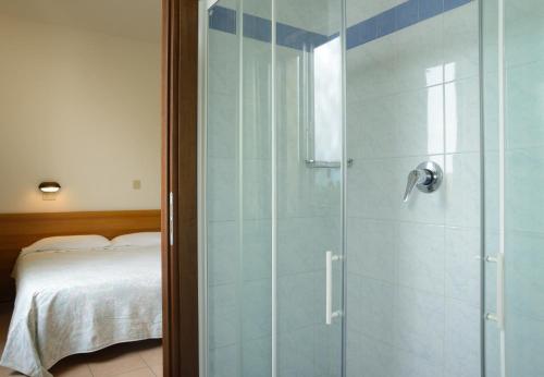 チェゼナーティコにあるHotel Acaciaのベッドルーム(ガラス張りのシャワー、ベッド付)
