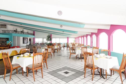 un restaurant avec des tables blanches, des chaises et des fenêtres dans l'établissement Grand Hotel KYRIOS Veracruz, à Veracruz