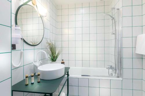 een badkamer met een wastafel, een bad en een spiegel bij Hotel Saint Regis in Chalon-sur-Saône