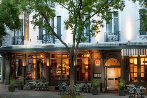 a building with tables and chairs in front of it at Hotel Saint Regis in Chalon-sur-Saône