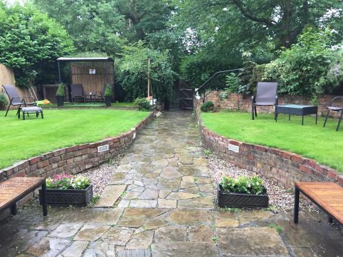 a garden with two benches and a stone path at Queens Guesthouse Manchester in Manchester
