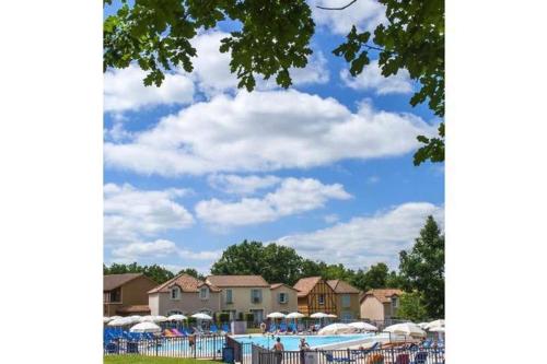 une piscine avec des tables et des parasols dans un parc dans l'établissement Residence du Lac,Apt 2P, 5 pers,Monflanquin, à Monflanquin