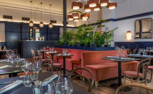 a restaurant with tables and chairs and plants at Hotel Saint Regis in Chalon-sur-Saône