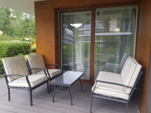 three chairs and a table on a porch at Family Apartment Golden Tulip 2 in Międzyzdroje